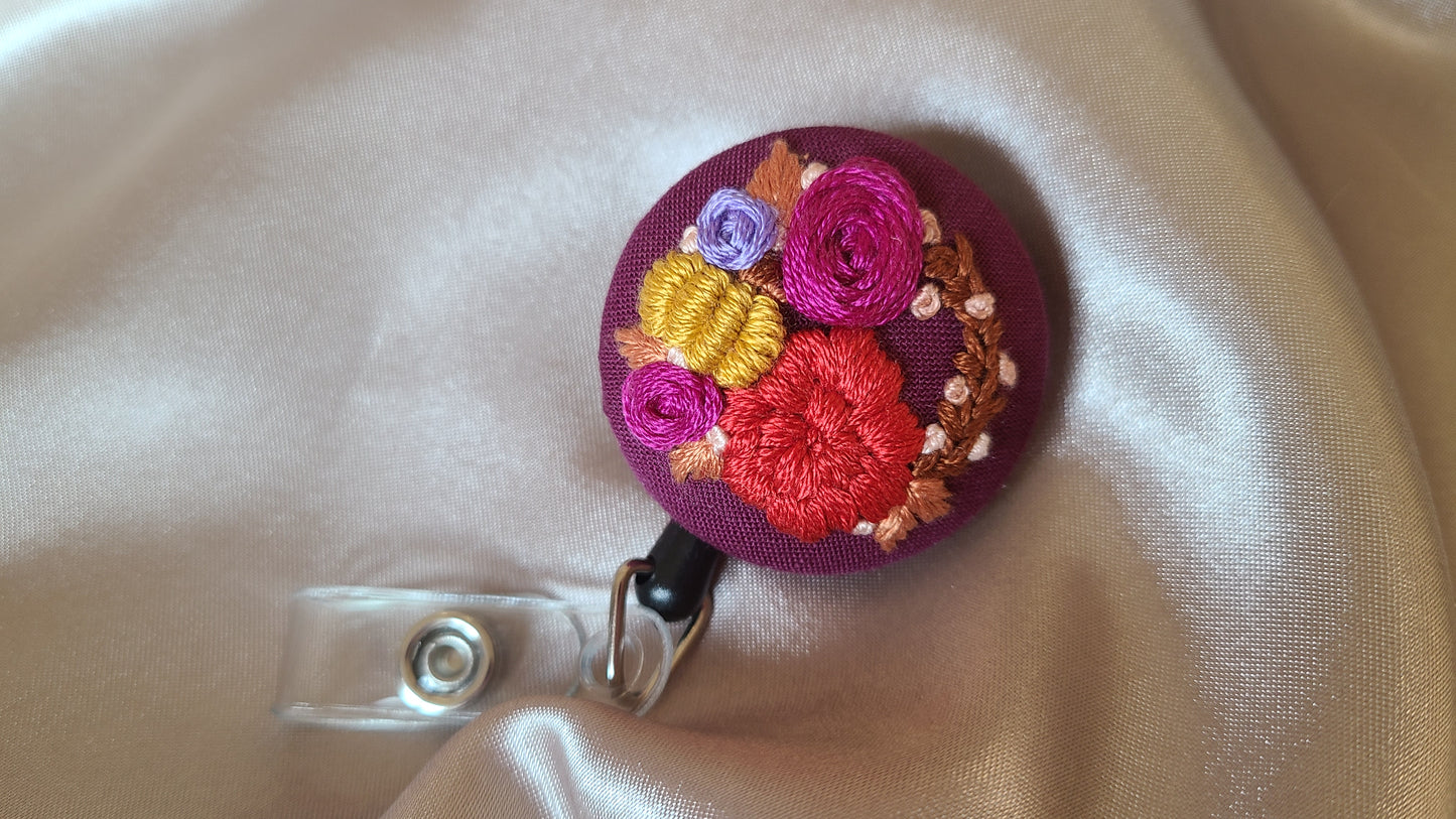 Red and Magenta Floral Wreath with Mini Golden Pumpkin Wreath on Dark Plum Hand Embroidered Retractable Badge Reel
